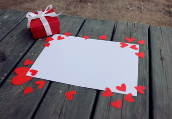 Red gift and white paper on wooden table