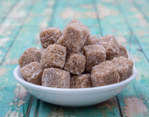 Sugarcane sugar cube in white bowl over wooden background