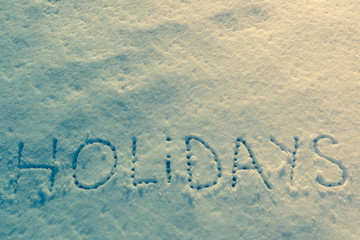 Written words Holidays on a snow field. Vintage filter applied.