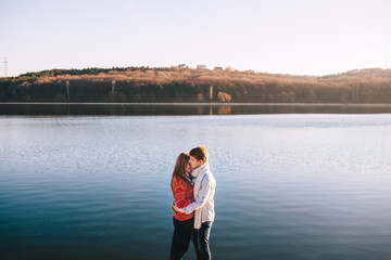 Fototapeta premium Teenage lovers embracing each other by a lake in autumn day