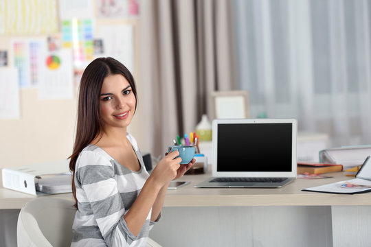 A beautiful young woman with a cup of tea working at home as a freelancer