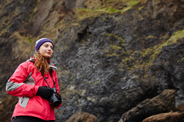 Naklejka na ściany i meble Young traveler woman holding camera in Iceland. Beautiful cauca