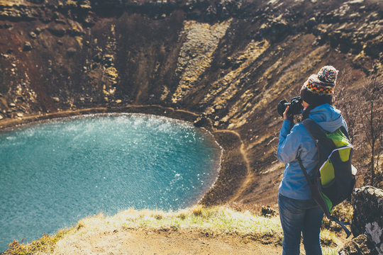 Back view of woman taking pictures in Kerid volcano crater, Icel