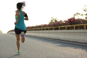 young woman runner running on city bridge road