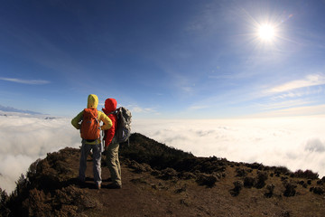 Fototapeta premium two successful backpacker enjoy the beautiful landscape at sunrise mountain peak