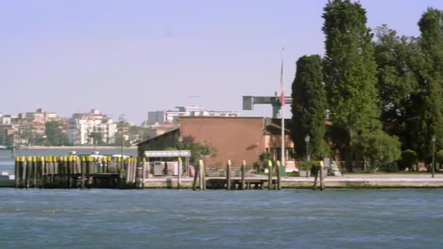 Tight panning shot of the east side of Giudecca from across the canal at a marina.
