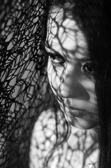 Headshot brunette model using patterned shadows as artistic effect on face while posing