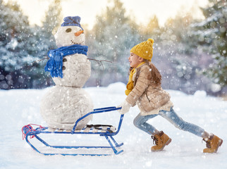 girl plaing with a snowman