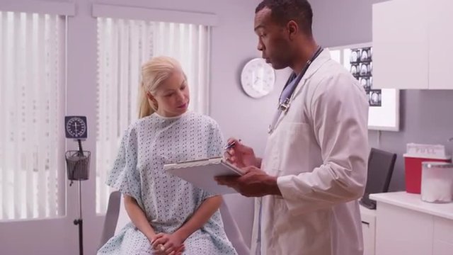 Black doctor writing down woman patient's medical history