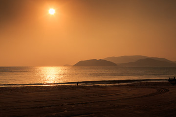 sunrise above sea against hills with running waves