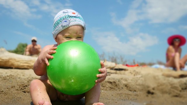 Cute baby boy playing with a ball on the beach