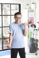 asian senior male with dumbell in the gym