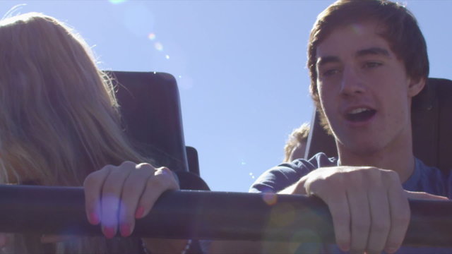 Rollercoaster, shot of young couple throwing arms in the air with excitement.