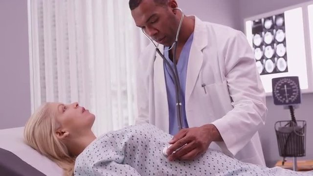 Black doctor listening to woman's belly