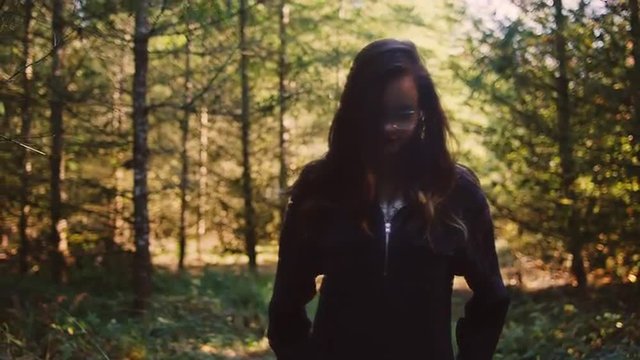 Beautiful girl in a forest walking toward the camera, slow motion, bokeh