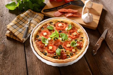 Tart (Quiche) with tomatoes, basil, salami, black olives and che