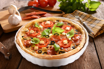 Tart (Quiche) with tomatoes, basil, salami, black olives and che