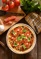 Tart (Quiche) with tomatoes, basil, salami, black olives and che