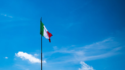 Italian flag waving in the sky with clouds, Monte Grappa, Italia.