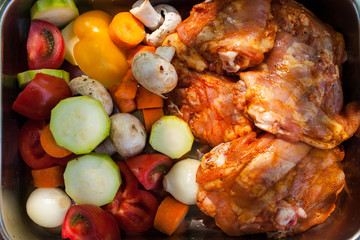 Raw chicken fillet with potatoes, tomatoes, mushrooms, peppers in cast-iron cauldron