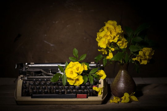 Still life with old typewriter with yellow flowers on wooden tab