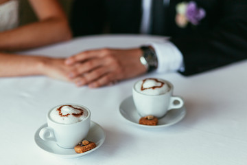 bride's and groom's hands holding each other on a table with two
