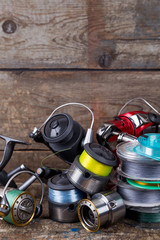 fishing reels and spoole with line on wooden background