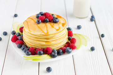 Stack of Sweet Pancakes with Fresh Blueberry, Raspberry, Apple and Maple Syrup on White Light Background