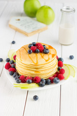 Stack of Sweet Pancakes with Fresh Blueberry, Raspberry, Apple and Maple Syrup on White Light Background