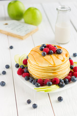 Stack of Sweet Pancakes with Fresh Blueberry, Raspberry, Apple and Maple Syrup on White Light Background