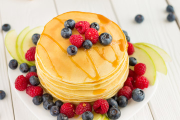 Stack of Sweet Pancakes with Fresh Blueberry, Raspberry, Apple and Maple Syrup on White Light Background, Horizontal, Top View