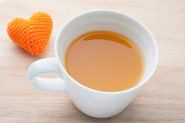 Orange juice and knitted fabrics heart shape on wooden backgroun