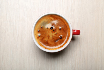 Cup of coffee on light background, top view