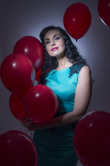 Happy young woman with red latex balloons