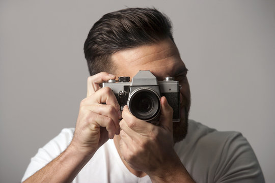 Handsome man holding manual film camera taking picture