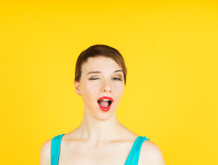 funny and winking woman portrait on yellow background
