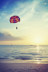 Vintage stylized picture of parasailing at sunset, summer adventure concept, Malaysia.