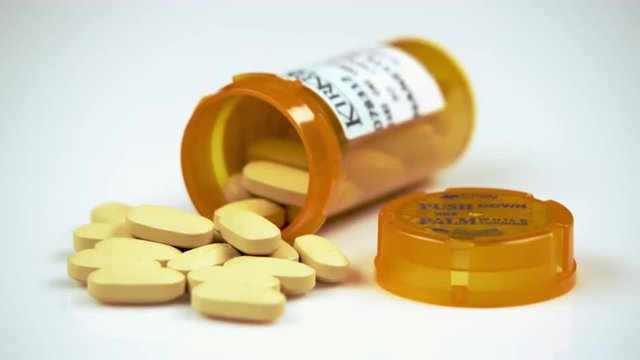 Yellow pills in an open prescription bottle.
