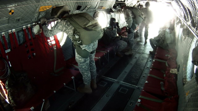 Paratroopers looking out the windows of a CH-47 Chinook helicopter.