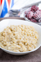 Oatmeal porridge and frozen blackberries on background. Healthy british breakfast