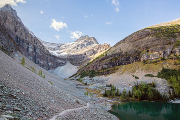 hiking trail in the middle of a pile of rocks in front of a peak and close to a lake in the national park of banff in the rocky mountains of alberta canada