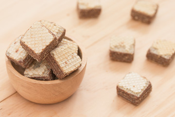 Wafers with chocolate in cup on wooden background.