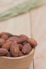 Almonds in cup on wooden background.