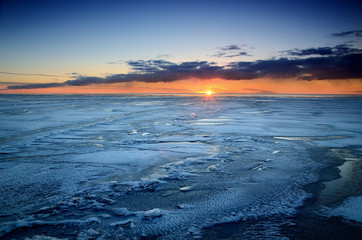 colorful sunset at the snowy Baltic sea shore