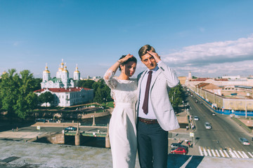 Obraz na płótnie Canvas beautiful wedding couple together on the roof of a tall building