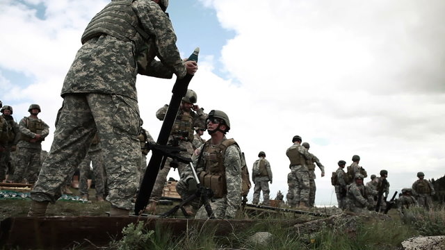 Group of soldiers firing a mortar launcher with instructors.