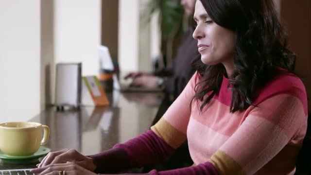 Panning view from womans face to laptop while she is using touch pad.