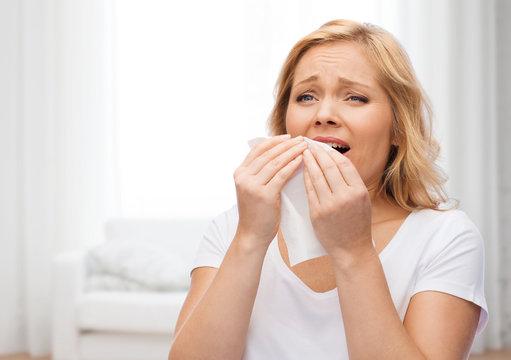 unhappy woman with paper napkin sneezing