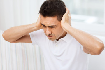 unhappy man closing his ears by hands at home