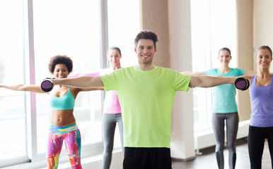 group of smiling people working out with dumbbells